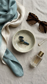 Handmade trinket dish with crescent moon styled on linen fabric with scarf, sunglasses and perfume – Gin Ceramics