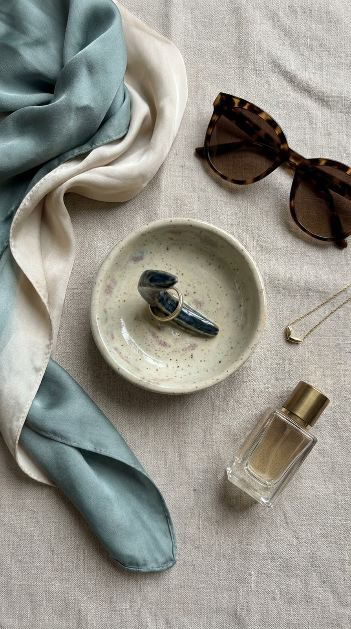 Handmade trinket dish with crescent moon styled on linen fabric with scarf, sunglasses and perfume – Gin Ceramics detail