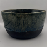 Moody dark glossy variegated ceramic serving bowl on white background